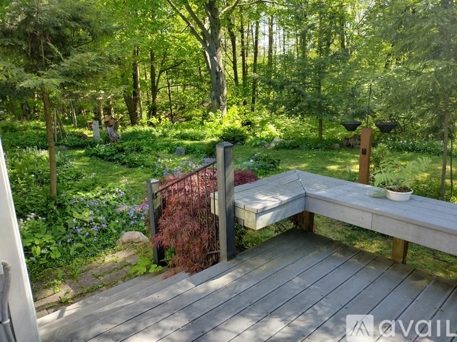 A wooden deck with a bench and a hanging light fixture in a lush green garden.