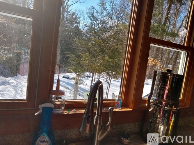 A kitchen sink with a window showing a snowy landscape outside.
