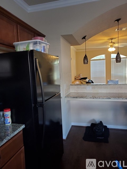 A black refrigerator with a few items on top and a black bag on the floor.