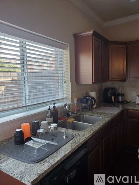 A kitchen with a sink, a window with blinds, and wooden cabinets.