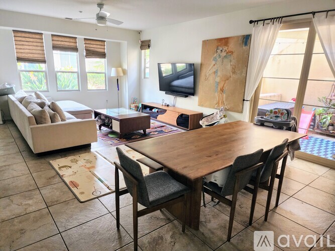 A living room with a television, a couch, a table, and chairs.