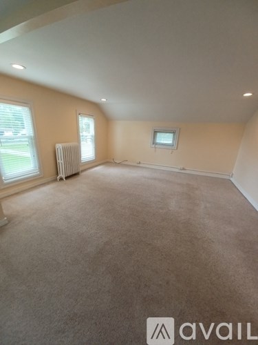 A room with beige carpet and a window.