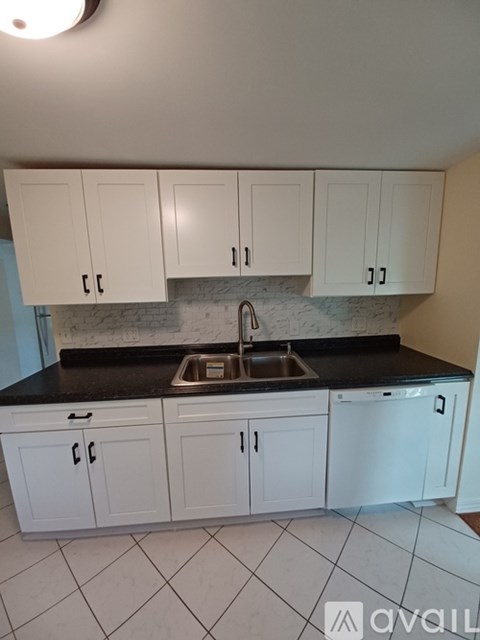 A kitchen with white cabinets and a black countertop.