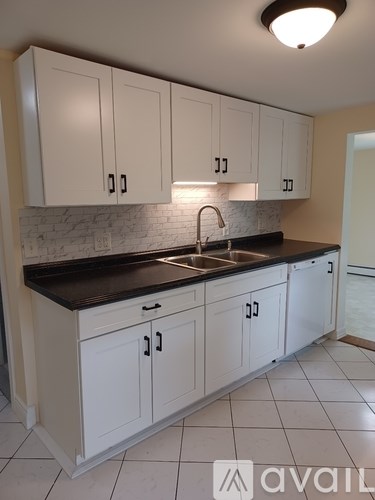 A kitchen with white cabinets and a black countertop.