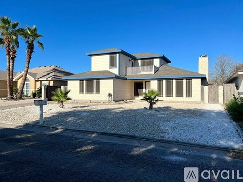 A house with a gravel driveway and palm trees in front.
