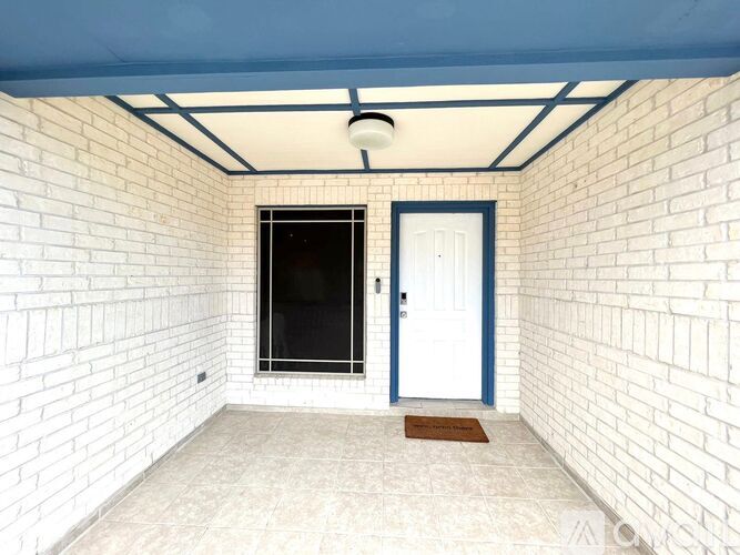 A white brick wall with a blue door and a window.