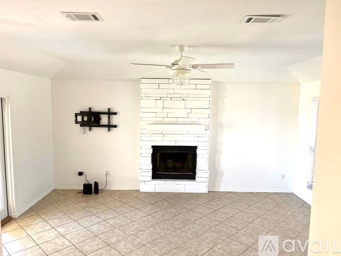 A living room with a fireplace and a fan on the ceiling.