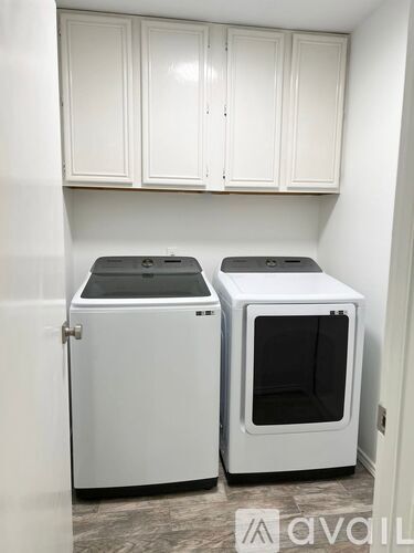 Two white ovens in a kitchen with white cabinets.