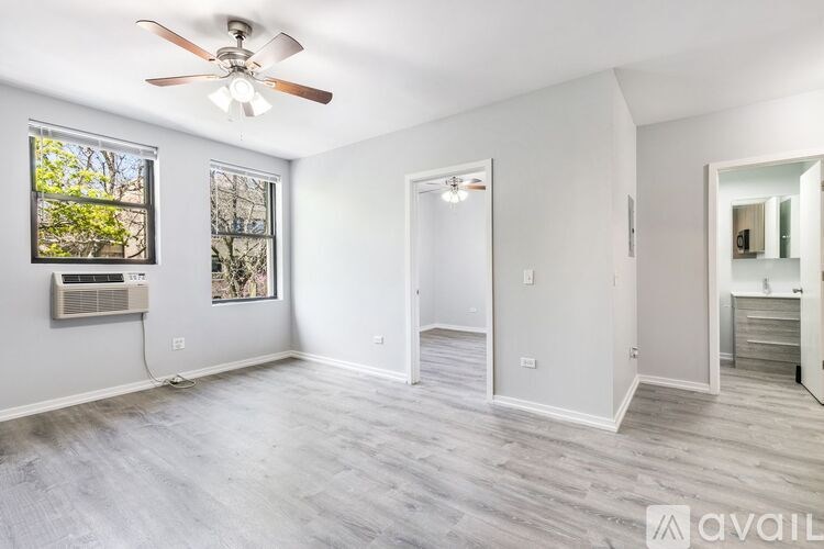 A spacious room with a ceiling fan and a window with a view of trees.