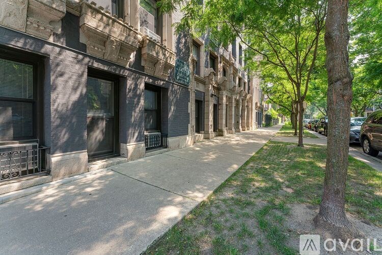 A tree stands on a sidewalk in front of a building.
