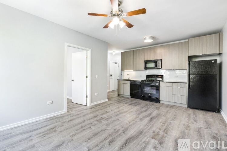 A kitchen with black appliances and wooden floors.