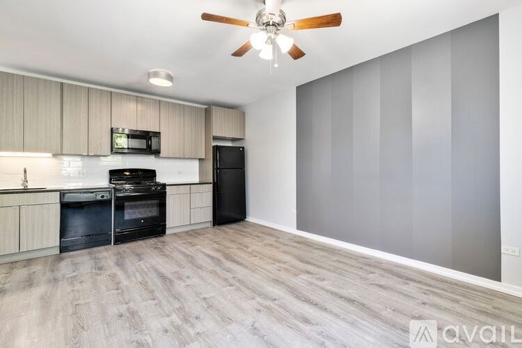 A spacious kitchen with a black oven and microwave, and a ceiling fan.