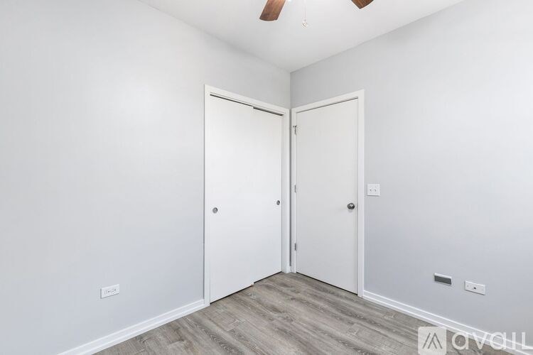 A room with two white doors and a wooden floor.