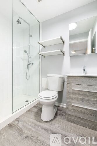 A white toilet in a modern bathroom with a walk-in shower.