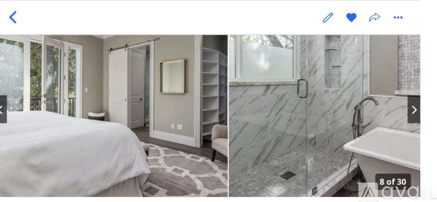A bedroom with a large bed and a bathroom with a walk-in shower.