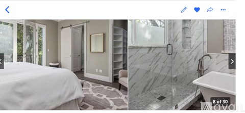 A bedroom with a large bed and a bathroom with a walk-in shower.