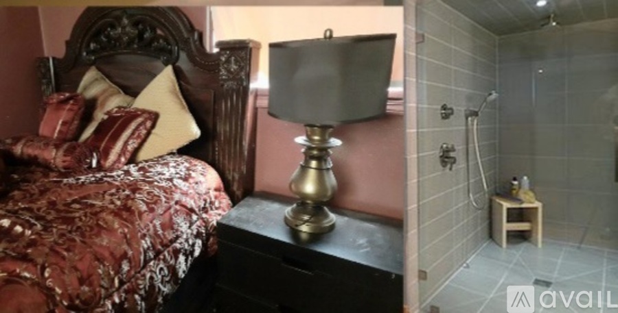 A bedroom with a bed, a lamp, and a shower.