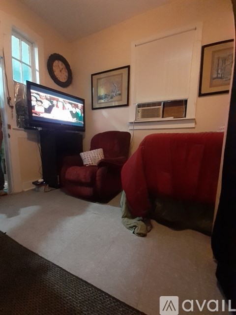 A living room with a red couch and a television on a stand.