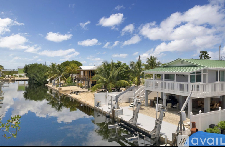 A house with a green roof is situated by a body of water.