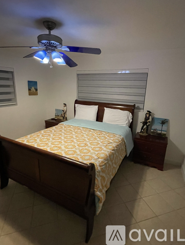 A bedroom with a bed, nightstand, and a ceiling fan.