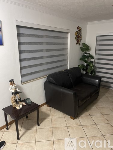 A black leather couch sits in a living room with a wooden table in front of it.