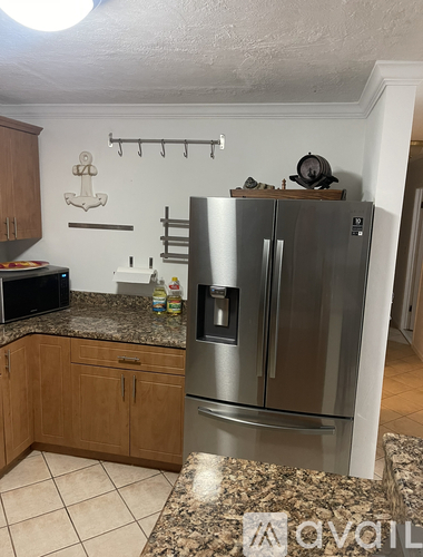 A kitchen with a stainless steel refrigerator and wooden cabinets.
