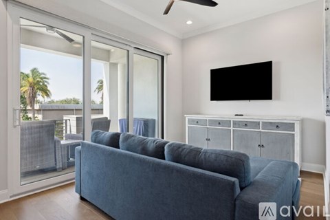 A living room with a grey couch and a flat screen TV mounted on the wall.