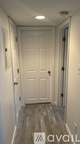 A hallway with a white door and a wooden floor.