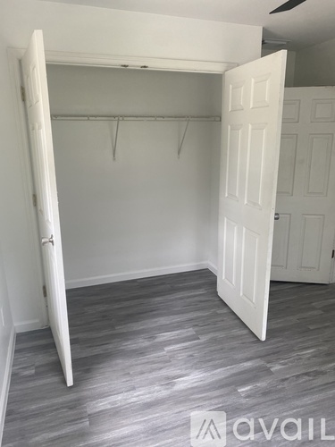A room with a white door and a grey floor.