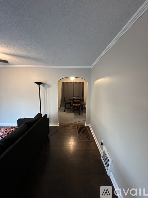 A living room with a black couch and a lamp.