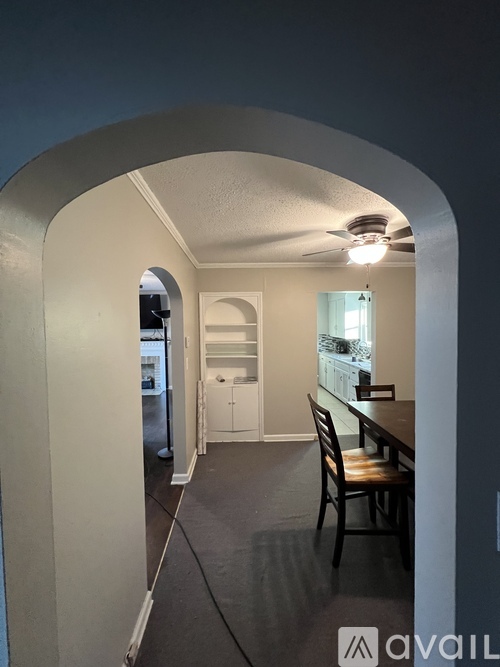 A hallway with a table and chairs leading to a bathroom.
