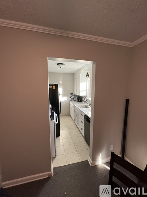 A kitchen with a refrigerator, sink, and cabinets is visible through an open door.
