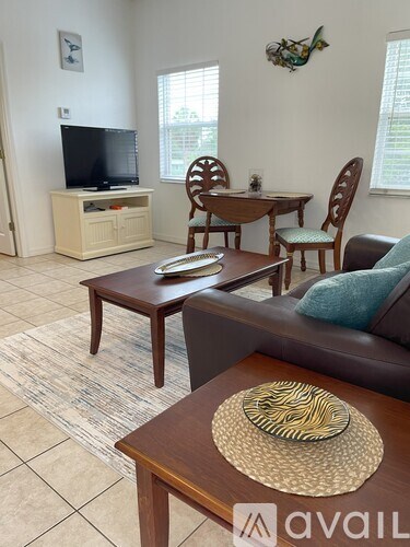 A living room with a brown sofa, a wooden coffee table, and a television on a cabinet.