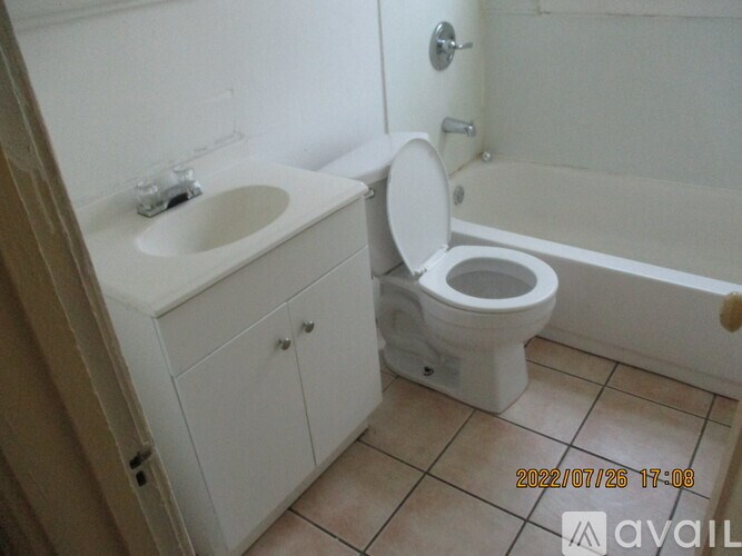 A white toilet is in a bathroom with a sink and a bathtub.