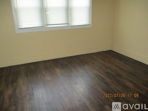 A room with wooden flooring and a window with blinds.