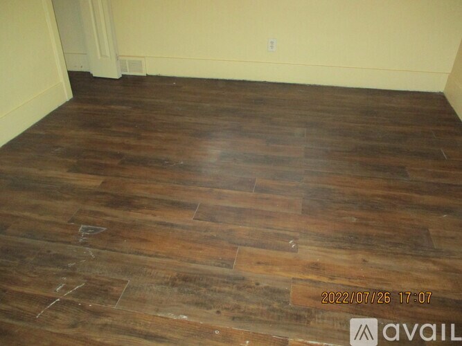 A room with wooden flooring and a wall in the background.