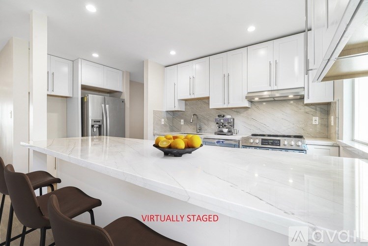 A kitchen with white cabinets and a marble countertop.