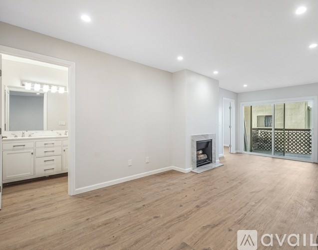 A spacious living room with a fireplace and a sliding glass door leading to a balcony.