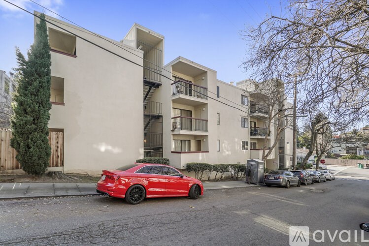 A red car is parked in front of a building with a sign that reads "avail".