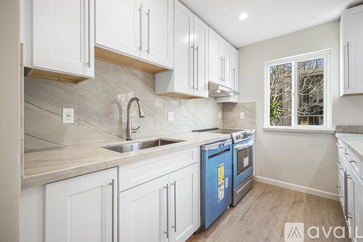 A kitchen with white cabinets and a blue dishwasher.