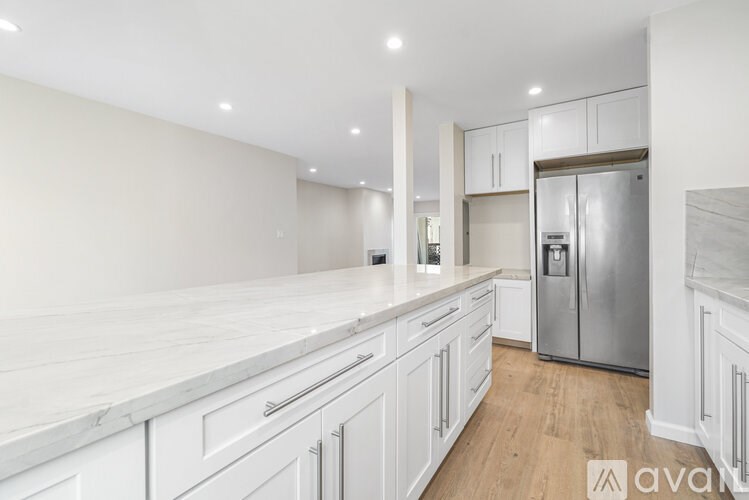 A kitchen with white cabinets and a refrigerator.