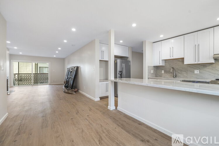 A spacious kitchen with white cabinets and a wooden floor.