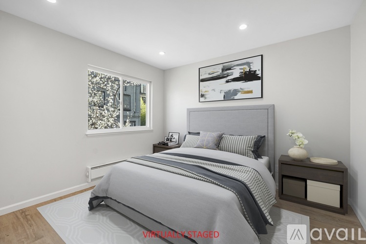 A bedroom with a large bed and a window with a view of a cityscape.