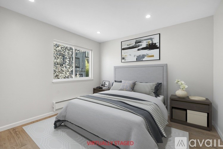 A bedroom with a large bed and a window with a view of a cityscape.