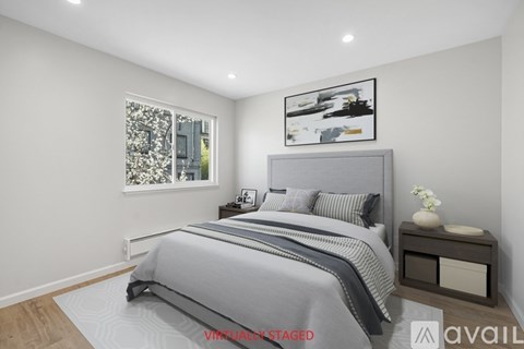 A bedroom with a large bed and a window with a view of a cityscape.