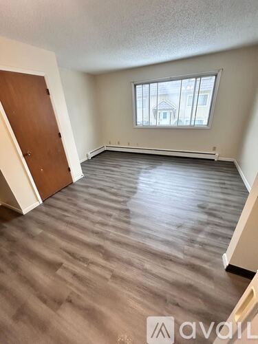 A room with wooden flooring and a window overlooking a house.