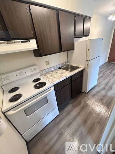 A kitchen with white appliances and brown cabinets.