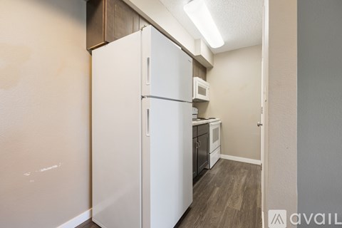 A white refrigerator in a kitchen with wooden cabinets.