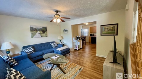 A living room with a blue couch and a ceiling fan.