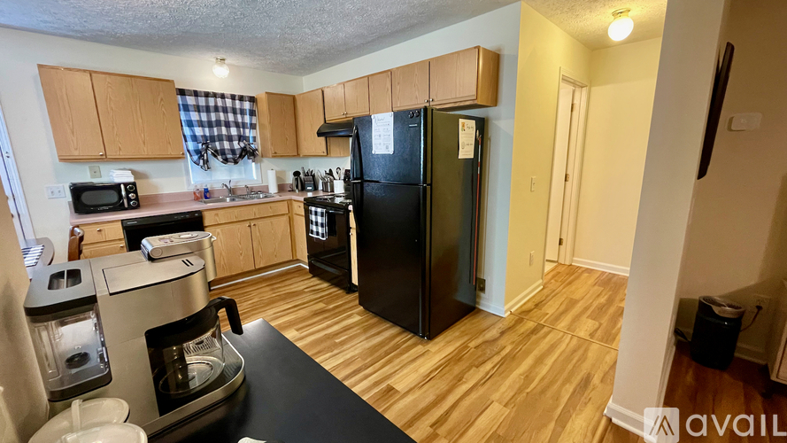 A kitchen with wooden cabinets and a black fridge.